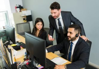 Male supervisor training a latin executive at a call center. Manager explaining work stuff to the employees offering tech support and customer service